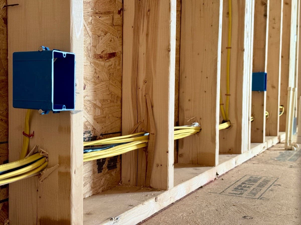 A row of outlet boxes on wall studs with cable run through to each one